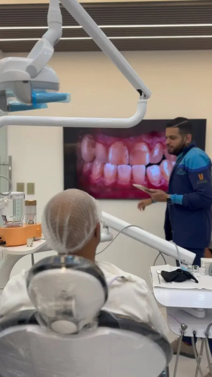 Кабинет консультации в J R Estetica Dental с пациентом и стоматологом, цифровой экран