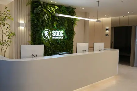 Área de recepción en Samsung Global Orthopedic Clinic con diseño moderno y pared verde