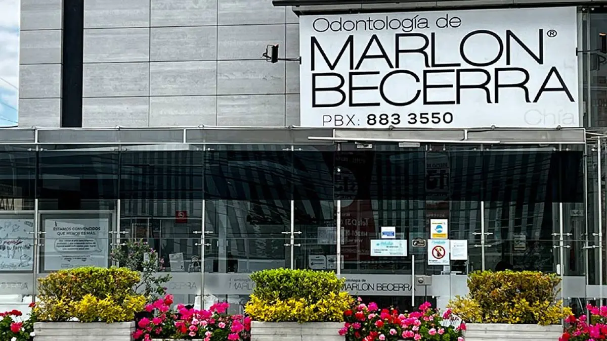 Clinic facade of Marlon Becerra Dentistry with glass entrance and flower beds