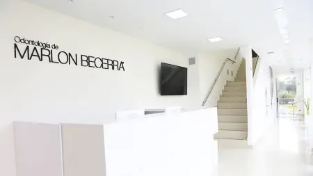 Área de recepción en Odontología Marlon Becerra con interior blanco moderno