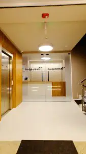 Área de recepción en la clínica Body Institute con entrada de vidrio moderno y detalles en madera