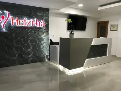 Mostrador de recepción moderno en la clínica Hefzi-bá con pared de logo iluminada