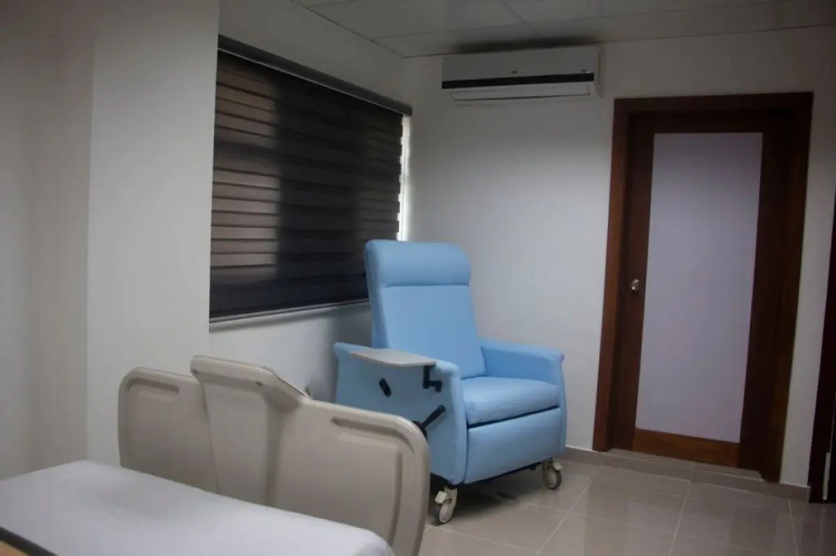 Patient room at DOCAMED clinic with hospital bed and medical recliner