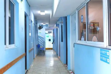 ممر عيادة دي فاميليا لا رومانا بجدران زرقاء ومقاعد للمرضى