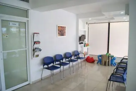 غرفة انتظار في عيادة Ortho Oral مع كراسي زرقاء ومنطقة ألعاب للأطفال